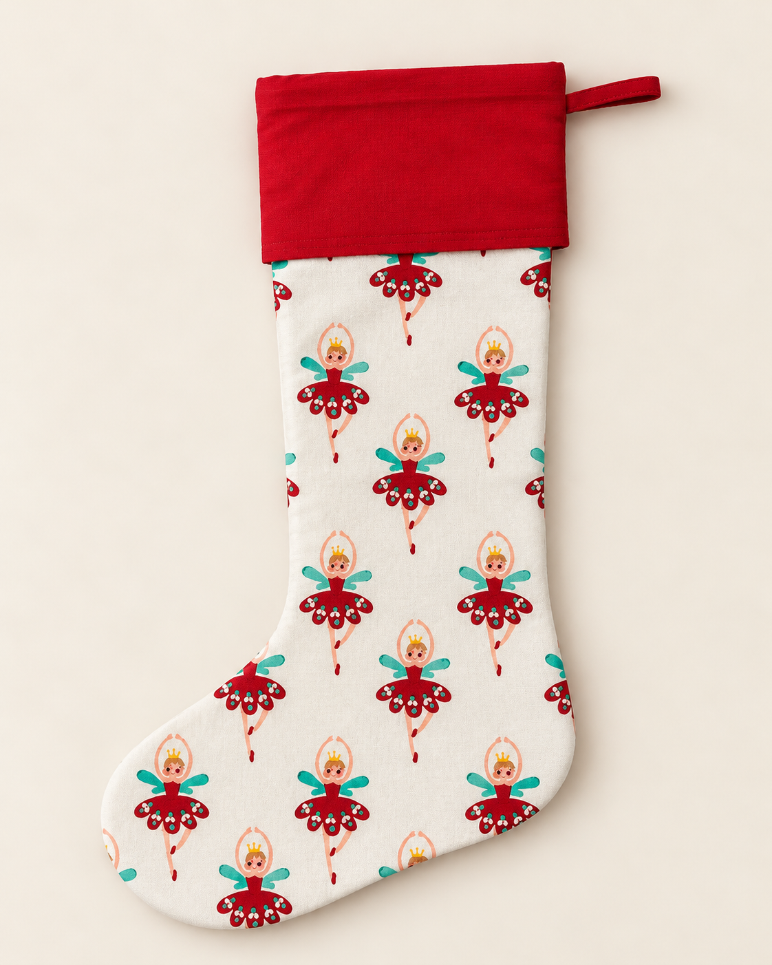 A Christmas stocking with a red fabric cuff and a white body printed with a repeating pattern of ballerina dancers in red and teal outfits, shown against a plain light beige background.