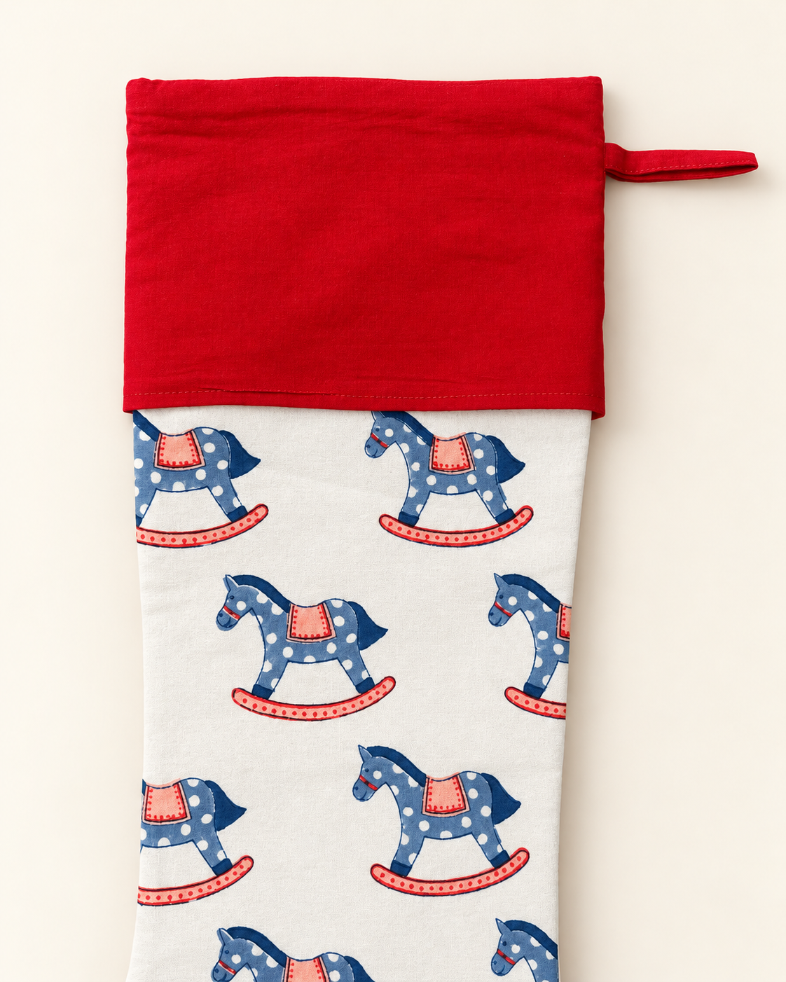  Close-up of blue and pink rocking horse print, red cotton cuff and stitching on a Kapara Christmas stocking.
